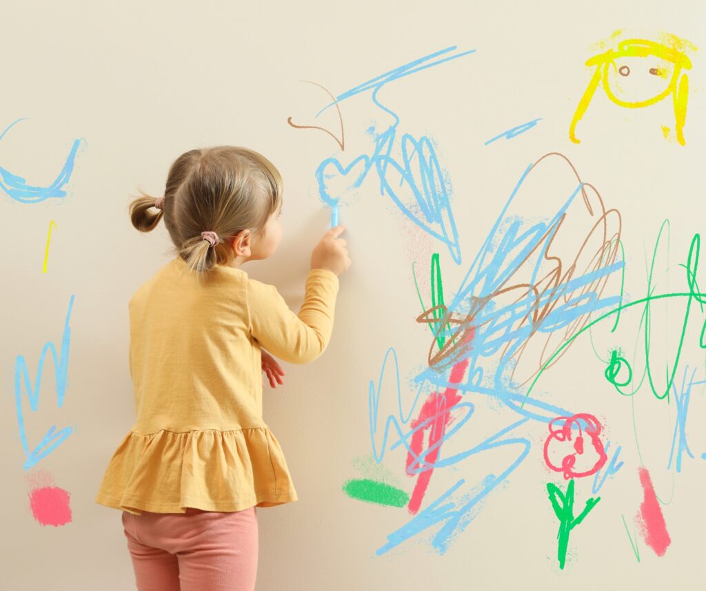 Little Child Drawing on White Wall, Back View